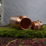Die 'Copper Serenity Elegance' - eine Kupferflasche, die mehr ist als nur ein Gefäß. Mit ihrer erhabenen Höhe von 27,5 cm und der matten satinierten Politur strahlt sie zeitlose Eleganz aus. Die Oberfläche, empfindlich und doch charmant, erzählt Geschichten von jeder Begegnung mit Wasser und Haut. Dieses Bild erfasst den Moment, in dem Funktion auf Stil trifft – ein visuelles Fest für die Sinne.