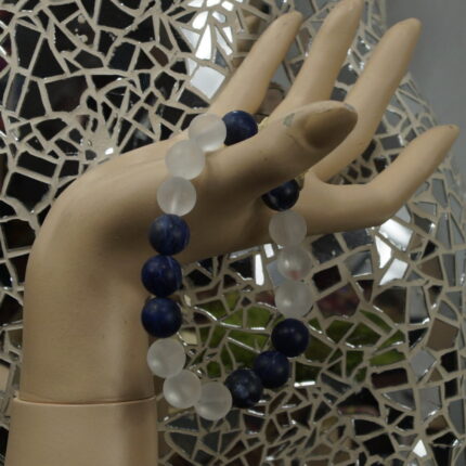 "Kristallklarer Geist" – Dieses Yogaarmband vereint Bergkristall und Sodalith für einen klaren Verstand und erhebende Intuition. Bergkristall bringt Klarheit, während Sodalith mit seiner tiefen, blauen Farbe den Weg der Wahrheit weist. Gemeinsam bilden sie ein dynamisches Duo, das das Stirn-Chakra stärkt und die Intuition fördert. Reinigen Sie das Armband unter fließendem Wasser und laden Sie es im Mondlicht auf, um die kraftvolle Verbindung zu erneuern.