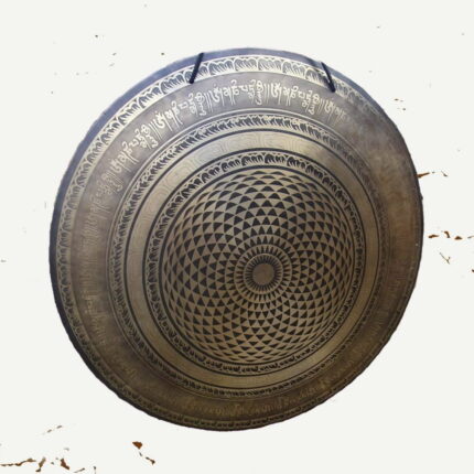 die Schönheit des Klangs mit unserem prachtvollen Bronce-Gong. Ein Kunstwerk aus der Mitte strömender Dreiecke, die sich spiralförmig nach außen verteilen und in kunstvoll verzierten Ringen enden, auf denen ein heiliges Mantra in Sanskrit ruht. Über allem thronen faszinierende Verzierungen, die diesem majestätischen Instrument eine Aura der Erhabenheit verleihen.